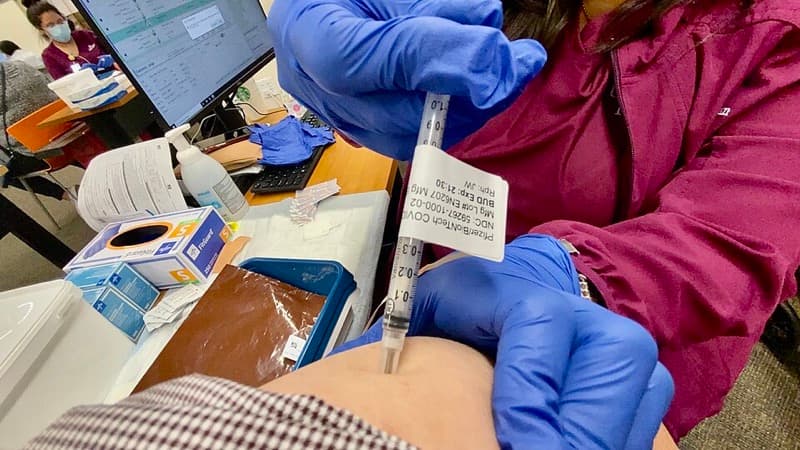 A healthcare worker preparing a vaccine dose in a syringe